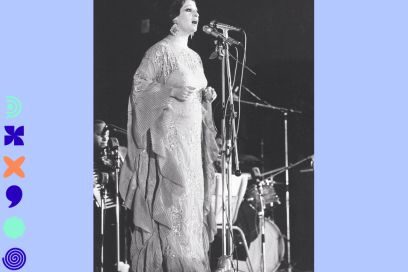 photo en noir et blanc des années 60 d'une chanteuse orientale de renom (Warda) sur une scène d'orchestre debout au micro en robe claire surmontée de broderies - Agrandir l'image, fenêtre modale