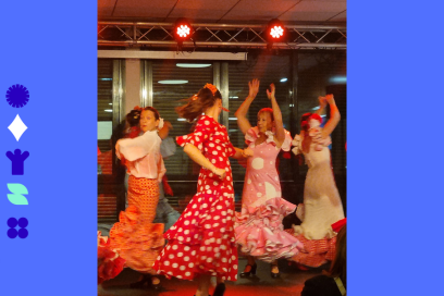 Photo des danseuses de Floréar en train d'effectuer une démonstration de flamenco sur une petite scène intérieure éclairée de projecteurs de lumière rouge, leurs robes typiques à pois virevolant - Agrandir l'image, fenêtre modale