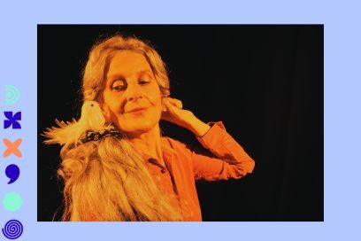 photo sur fond noir de la comédienne sous un éclairage de scène doré, cheveux blond ramassés en chignon, un petit oiseau blanc factice posé sur sa chevelure sur son épaule à gauche de l'image elle lui sourit avec tendresse, le bras gauche levé vers l'arrière de sa tête pour manipuler cet objet de scène qu'est l'oiseau. - Agrandir l'image, fenêtre modale