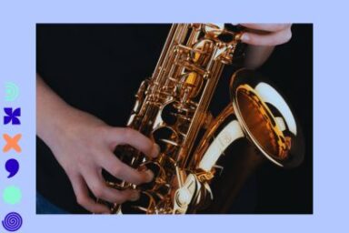 gros plan de mains de jeune homme en train de jouer du saxo, qui apparaît en majesté rutilant et doré