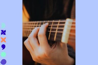 photo sépia en gros plan sur une main en train de jouer de la guitare sèche dans une lumière de scène tamisée,