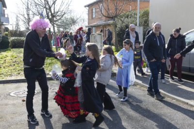 photo du défilé, des jeunes filles jettent des confettis, on voit les familles défiler derrière - Agrandir l'image 12 sur 17, fenêtre modale