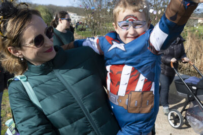 photo d'une femme qui tient un enfant dans ses bras, il est déguisé en captain America et jette des confettis devant lui - Agrandir l'image 15 sur 17, fenêtre modale
