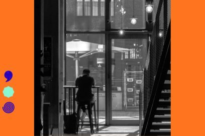 photo portrait en noir et blanc sur le thème "Habiter" et "Flou", où l'on voit la silhouette en ombres chinoises d'un homme assis sur un tabouret de bar dans un complexe urbain moderniste donnant par une baie vitrée sur une cour intérieure et sur la façade d'un immeuble aux fenêtres éclairées en arrière-plan - Agrandir l'image, fenêtre modale