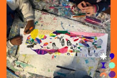 vue en plongée de mains d'enfants s'affairant sur un plan de travail d'atelier d'arts plastiques, jonché de papier et de traits de couleurs, pour dessiner une fresque colorée aux feutres sous la lumière d'une lampe de travail