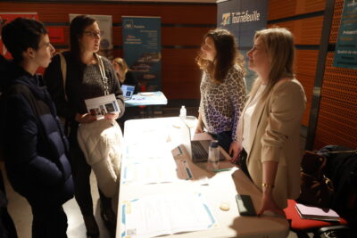photo d'un jeune garçon et d'une femme qui échangent avec deux femmes derrière un stand - Agrandir l'image 19 sur 22, fenêtre modale