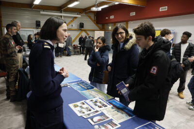 photo de deux jeunes qui échangent avec une femme en uniforme derrière un stand - Agrandir l'image 3 sur 22, fenêtre modale