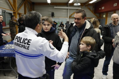 photo d'un jeune garçon et d'un enfant, avec un homme, qui échangent avec un policier municipal en uniforme - Agrandir l'image 5 sur 22, fenêtre modale