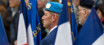 photo paysage de porte drapeaux à une cérémonie de commémoration, vus de derrière en biais avec les drapeaux français au premier plan