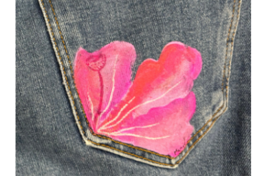 gros plan sur une pche arrière de jeans gris, rehaussée d'une fleur aux tons dégradés de rose avec effet de mouvement et pistil dessinés à la peinture en surimpression