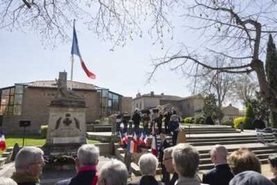 photo de la cérémonie prise depuis la foule, on voit l'orchestre jouer à côté du monument aux morts - Agrandir l'image 12 sur 16, fenêtre modale