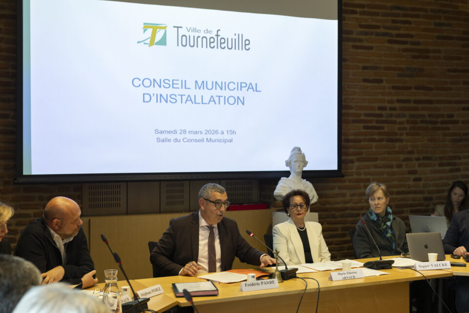 Photo de quatre personnes assises derrière une table, deux hommes et deux femmes, on voit derrière eux le buste de Marianne, et projeté sur une toile "Conseil municipal d'installation"