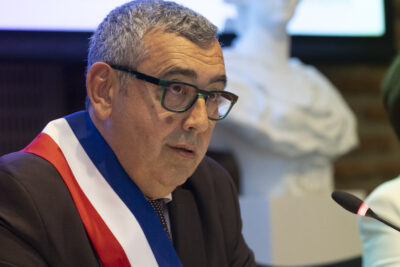 photo portrait du Maire qui porte l'écharpe, assis à table, derrière lui on voit le buste de Marianne - Agrandir l'image 3 sur 16, fenêtre modale