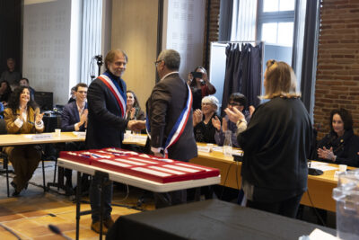 photo du Maire qui porte l'écharpe et serre la main à un élu qui la porte également - Agrandir l'image 10 sur 16, fenêtre modale