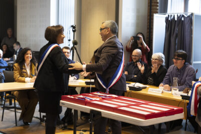 photo du Maire qui tient le bras d'une élue souriante qui porte l'écharpe - Agrandir l'image 11 sur 16, fenêtre modale