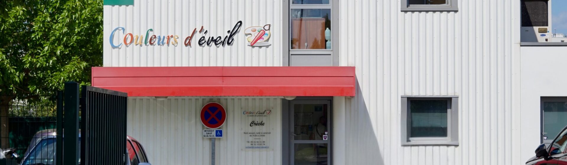 photo de la façade d'un petit immeuble avec des pointes de couleur et écrit "couleurs d'éveil"