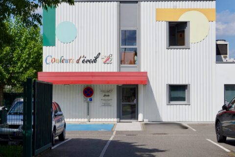 photo de la façade d'un petit immeuble avec des pointes de couleur et écrit "couleurs d'éveil"