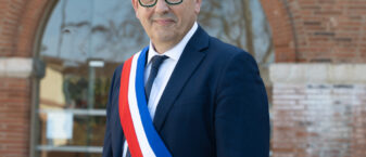 Photo portrait du Maire portant l'écharpe devant l'Hôtel de ville