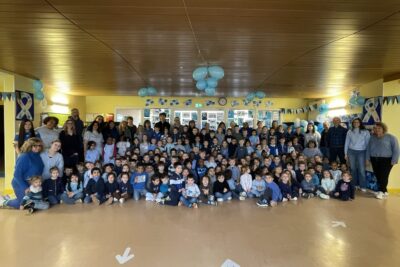 photo de groupe dans un hall d'école, tous les enfants de maternelle sont réunis, habillés en bleu et avec une déco de ballons bleus au dessus d'eux - Agrandir l'image 8 sur 16, fenêtre modale