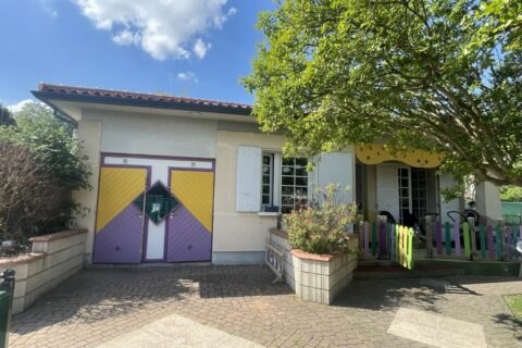 Photo de la façade d'une maison avec des portes colorées, sous un ciel bleu