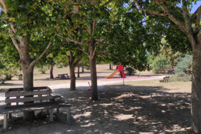 Photo d'une zone de verdure ombragée par des arbres avec bancs et aire de jeux - Agrandir l'image, fenêtre modale