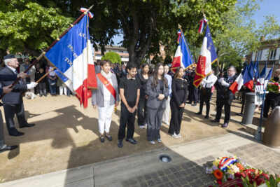 photo d'un groupe de cinq jeunes et d'une élue qui porte l'écharpe de la Région Occitanie qui se recueillent dans le square,face aux gerbes de fleurs, et entre les porteurs de drapeaux - Agrandir l'image 21 sur 26, fenêtre modale