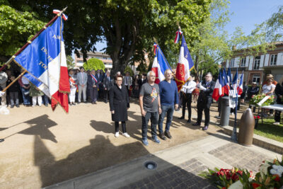 photo de deux hommes et une femme qui se recueillent dans le square ensoleillé avec deux rangées de porteurs de drapeaux sur le côté - Agrandir l'image 23 sur 26, fenêtre modale