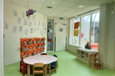 photo d'une petite pièce dans une crèche avec une table ronde et des petites chaises, des dessins accrochés au mur - Agrandir l'image 8 sur 10, fenêtre modale
