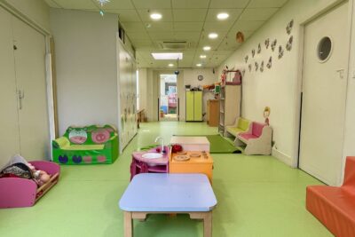 Photo d'une pièce de crèche avec petite table et petites assises, sol vert - Agrandir l'image 9 sur 10, fenêtre modale