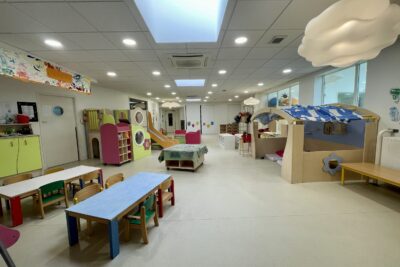 Photo d'une grande pièce dans une crèche, avec des petites tables, des structures de jeux et des lumières en forme de nuage - Agrandir l'image 10 sur 10, fenêtre modale