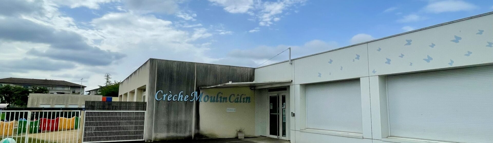 photo de façade d'entrée de la crèche Moulin Câlin sous un ciel bleu et nuages blancs