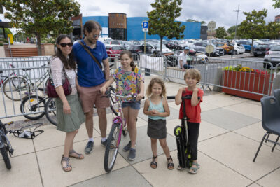photo d'une famille avec trois enfants,une jeune fille sur un vélo à l'arrêt, ils sourient à l'objectif - Agrandir l'image 9 sur 19, fenêtre modale