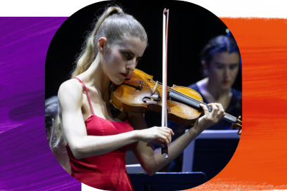 Plan rapproché sur la violoniste Manon Galy, de profil, cheveux longs blonds ramassés en queue de cheval en robe décolleté satinée de couleur rouge, jouant au milieu du parterre des musiciens de l'orchestre. - Agrandir l'image, fenêtre modale