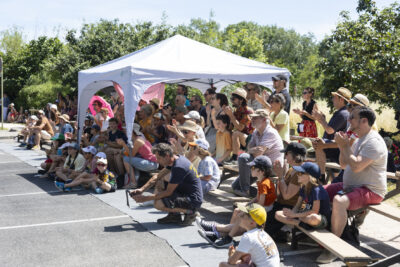photo du public assis sur des petits gradins dans un parc, qui applaudissent et regardent en face - Agrandir l'image 7 sur 15, fenêtre modale