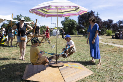photo de deux enfants qui jouent sur un jeu à bascule sous un parasol, dans un parc - Agrandir l'image 15 sur 15, fenêtre modale