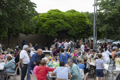 photo du repas partagé en extérieur, de nombreuses personnes rassemblées autour de longues tables, des familles et les élus - Agrandir l'image 11 sur 14, fenêtre modale
