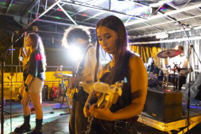 photo du groupe de jeunes en plein concert avec une jeune femme guitariste au premier plan - Agrandir l'image 10 sur 14, fenêtre modale