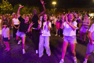 photo de jeunes qui sourient et applaudissent, derrière elles un peu de monde, il fait nuit - Agrandir l'image 12 sur 14, fenêtre modale