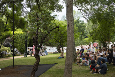 photo d'un spectacle dans un parc à l'ombre, avec de nombreuses familles assises dans l'herbe pour regarder - Agrandir l'image 4 sur 19, fenêtre modale