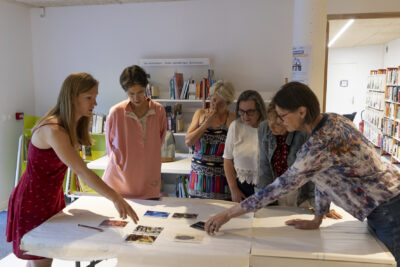 photo d'un groupe de six femmes debout autour d'une table, en train de placer des cartes - Agrandir l'image 7 sur 19, fenêtre modale