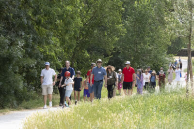 photo d'une trentaine de personnes qui marchent sur un chemin entouré de verdure, au soleil - Agrandir l'image 4 sur 13, fenêtre modale