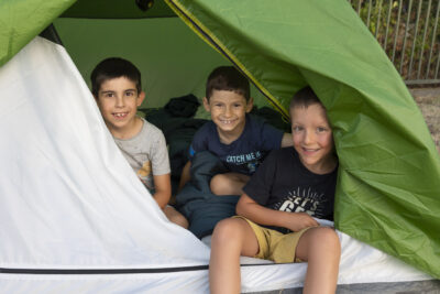 photo de trois garçons dans une tente ouverte qui sourient à l'objectif - Agrandir l'image 9 sur 21, fenêtre modale