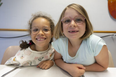 photo de deux jeunes filles assises à table qui regardent l'objectif en souriant - Agrandir l'image 7 sur 21, fenêtre modale