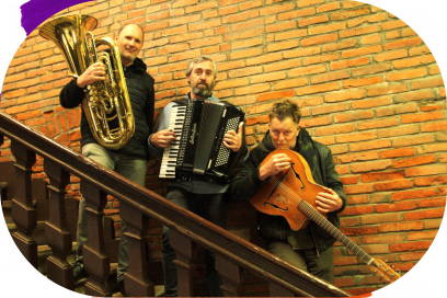 Alignés le long de la balustrade qui borde l'escalier qui relie la Daurade aux quais de la Garonne à Toulouse, dans un décor de briques et sous une lumière en sépia, les trois musiciens arborent leur instrument de musique respectif et leur sourire vers l'objectif situé plus bas. - Agrandir l'image, fenêtre modale