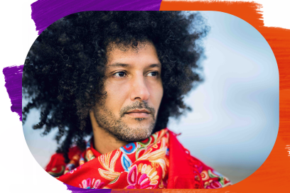 Plan rapproché sous forme de portrait couleur de Walid Ben Selim, visage de trois quarts tourné vers la droite de l'image, cheveux noirs frisés au vent, yeux et moustaches bien dessinés, un foulard bariolé au cou, il regarde hors champ dans un paysage que l'on devine maritime en arrière-plan. - Agrandir l'image, fenêtre modale