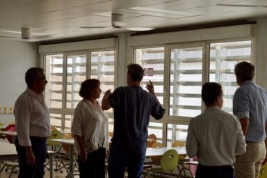 Photo paysage en intérieur, de cinq personnes, dans un réfectoire d'école, avec des brasseurs d'air au plafond