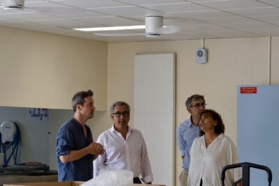 photo de quatre personnes dans une salle avec des tables et chaises colorées, il y a des brasseurs d'air au plafond - Agrandir l'image 2 sur 3, fenêtre modale