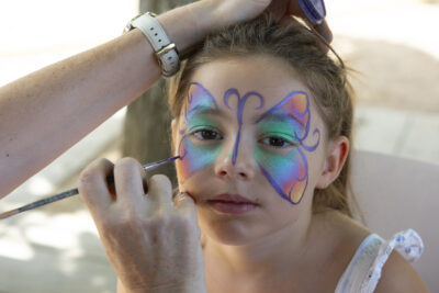 photo d'une jeune fille en train de se faire maquiller un papillon autour des yeux - Agrandir l'image 10 sur 15, fenêtre modale