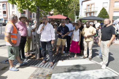 photo du Maire entouré des élus qui fait un discours, à l'ombre d'un arbre dans une rue - Agrandir l'image 4 sur 15, fenêtre modale