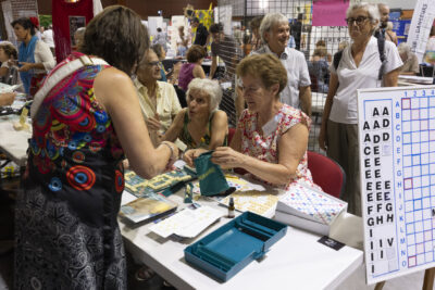 photo d'un stand avec deux femmes qui tendant un petit sac de scrabble et une femme qui prend des pièces - Agrandir l'image 13 sur 16, fenêtre modale
